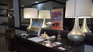 A reception desk with two lamps, a poster, and various items on the counter. - THE PARAGON of Golden Isles (Brunswick)