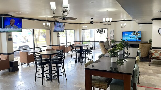 A spacious indoor area with multiple seating arrangements, including tables and chairs, and a television mounted on the wall. - THE PARAGON of Golden Isles (Brunswick)