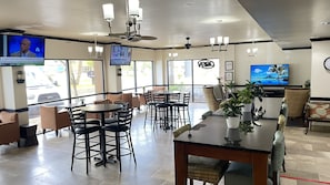 A spacious indoor area with multiple seating arrangements, including tables and chairs, and a television mounted on the wall. - THE PARAGON of Golden Isles (Brunswick)