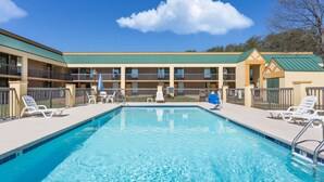 A pool area with lounge chairs and a building with multiple balconies. - Days Inn by Wyndham Mocksville (Mocksville)