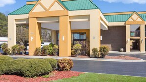 A modern hotel with a green roof, beige exterior, and a parking lot with red mulch landscaping. - Days Inn by Wyndham Mocksville (Mocksville)