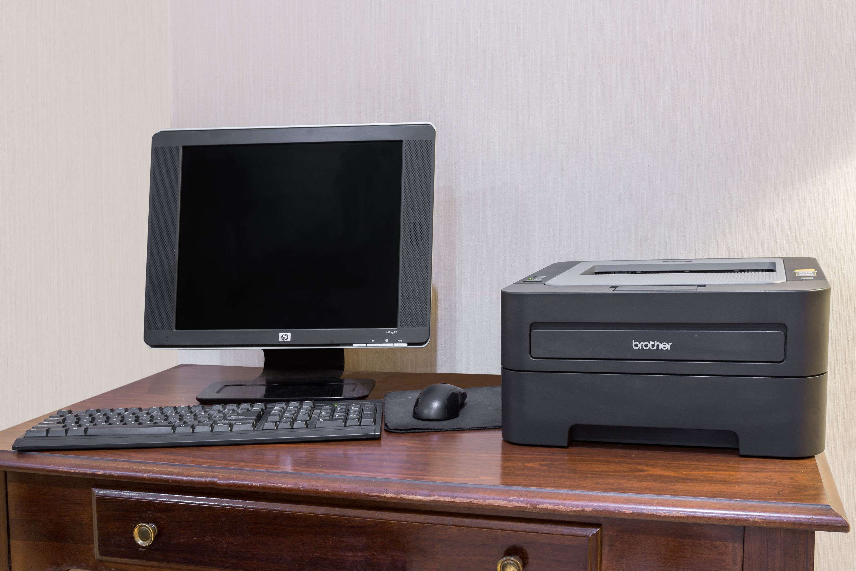 Un escritorio de madera con un monitor HP, una impresora Brother, un teclado y un ratón.