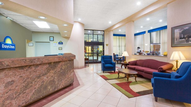 A hotel lobby with a reception desk, seating area, and a large window. - Days Inn by Wyndham Mocksville (Mocksville)