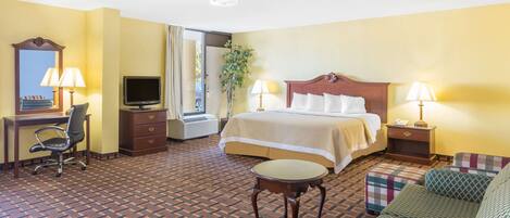 A hotel room with a bed, desk, chair, and a small table.