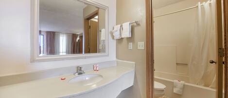 A bathroom with a sink, mirror, and shower.