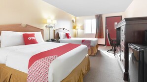 Une chambre d’hôtel avec deux lits, une commode, une télévision et un bureau.