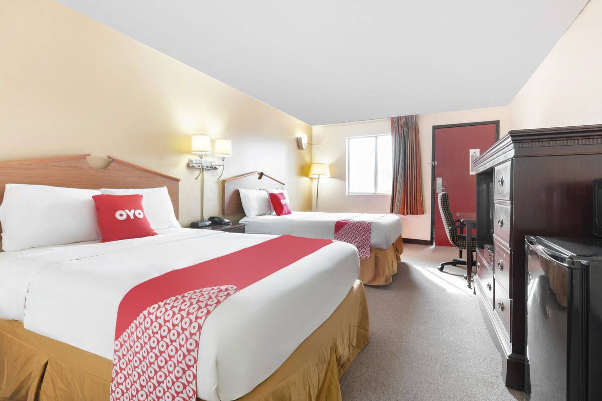 Habitación de hotel con dos camas, un aparador, un televisor y un escritorio.