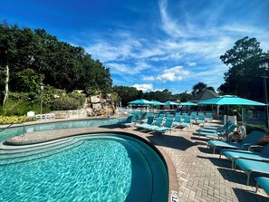 A swimming pool with lounge chairs and umbrellas, surrounded by trees and a rocky waterfall. - Innisbrook Resort (Palm Harbor)