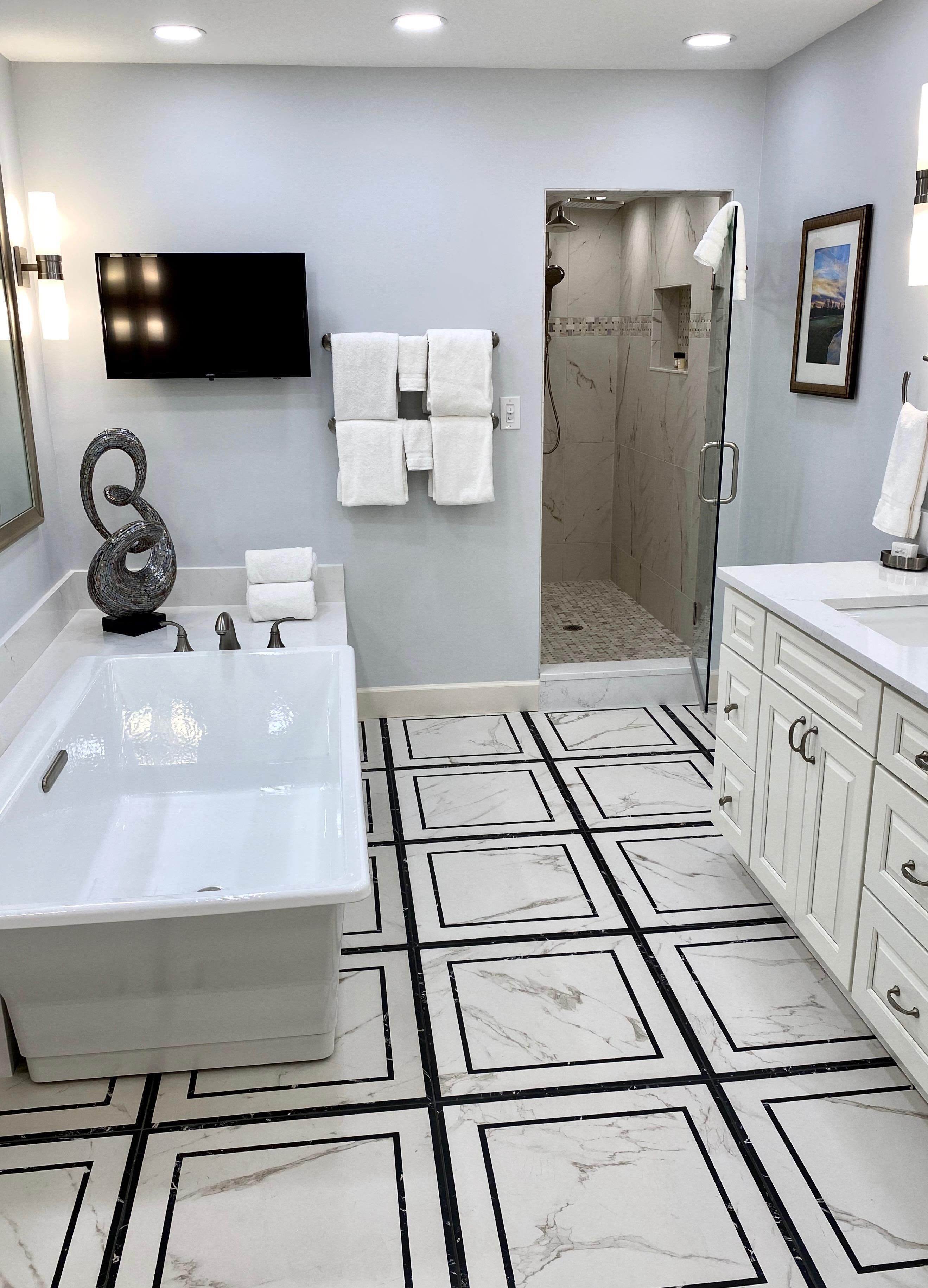 A modern bathroom with a large bathtub, a shower, and a vanity with cabinets.