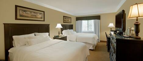 A hotel room with two beds, a desk, a dresser, and a television.