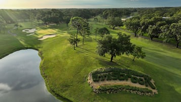 Un parcours de golf avec un étang, des arbres et un panneau indiquant « The Grove ».