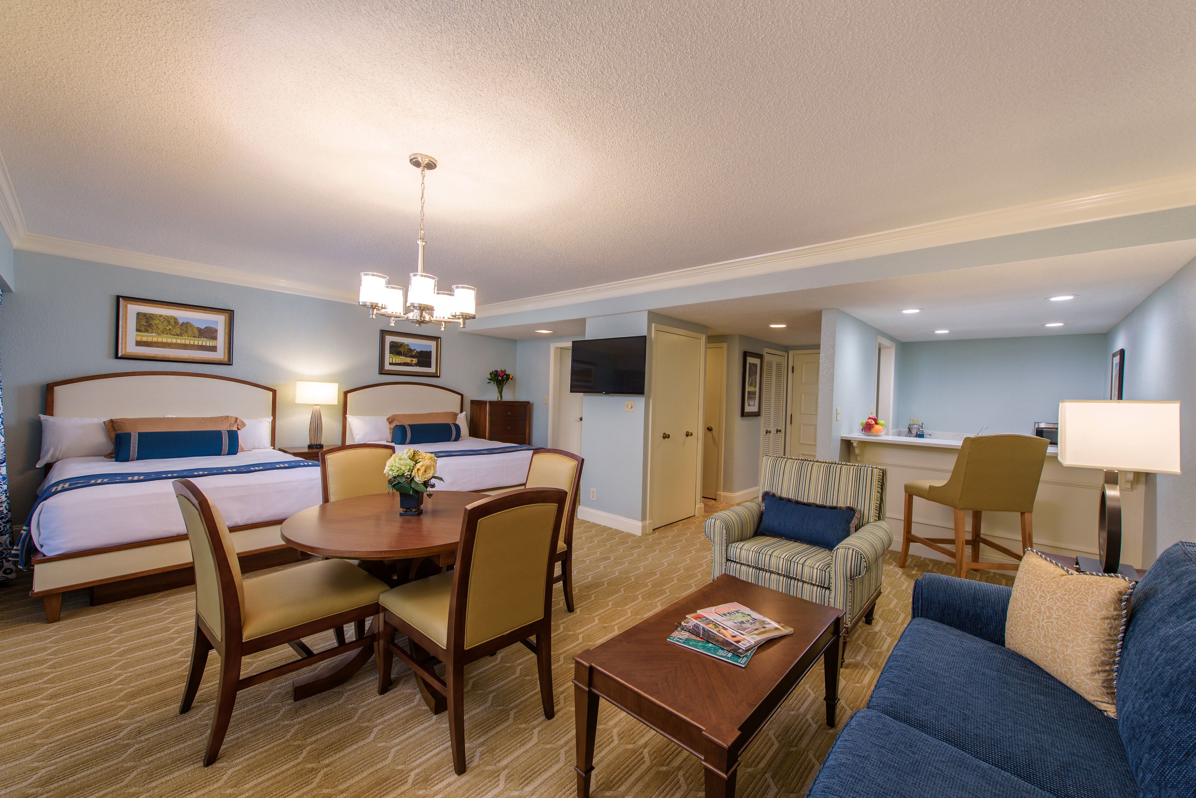 Une chambre d’hôtel avec deux lits, une table à manger, un canapé et un téléviseur dans un coin.