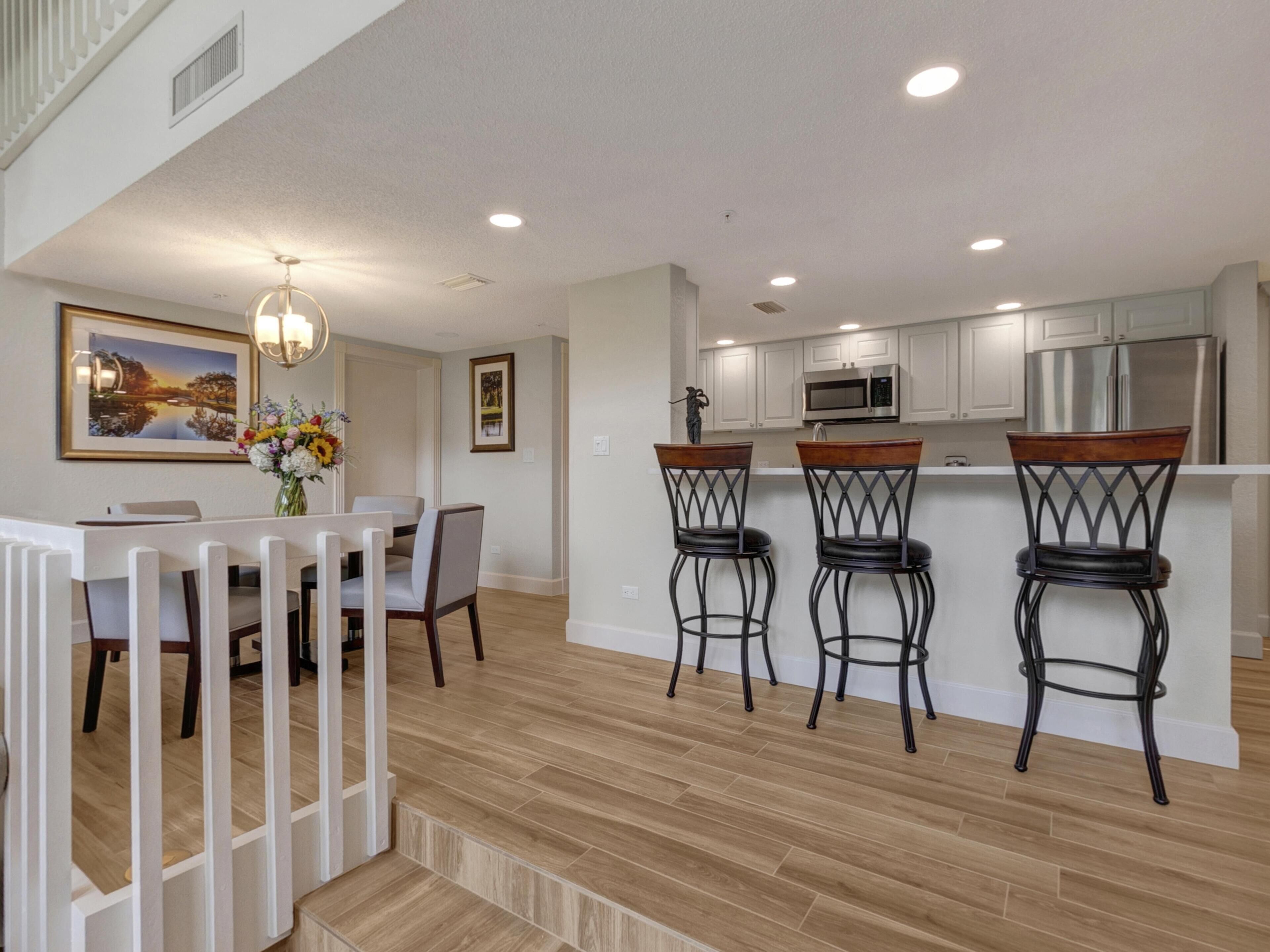 A modern kitchen with white cabinets, stainless steel appliances, and a wooden island with bar stools.