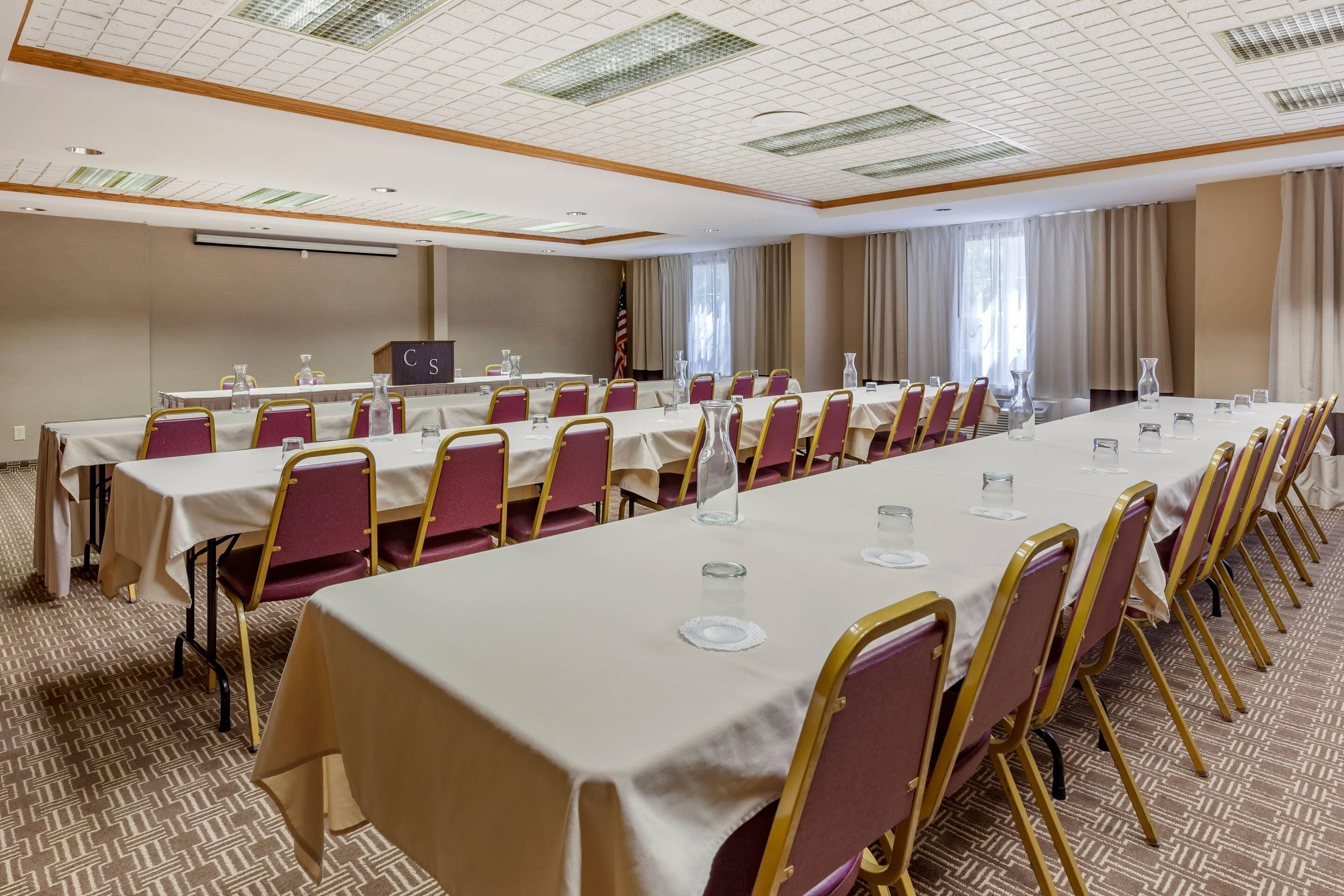 A conference room with long tables, chairs, and a podium.
