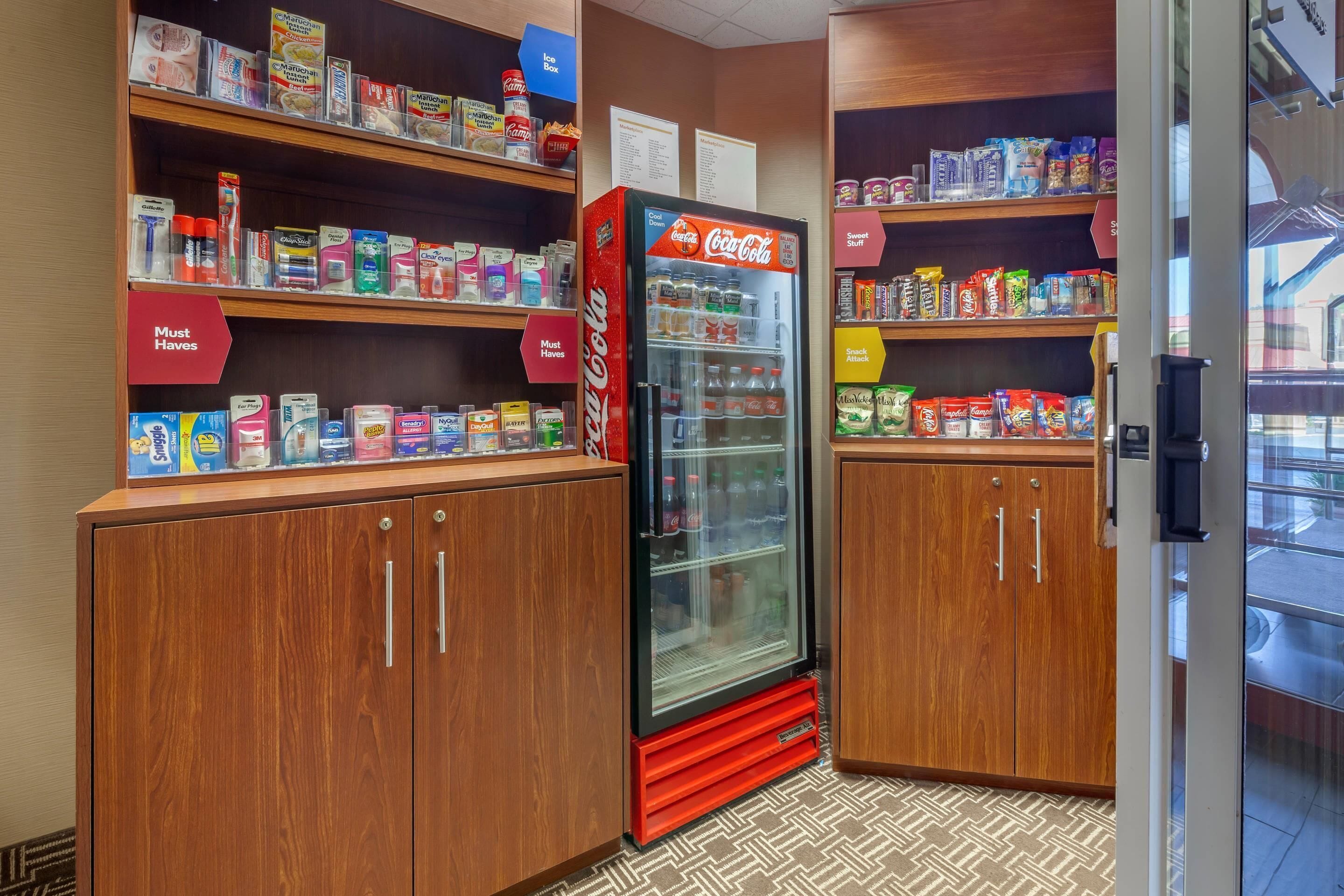 A hotel lobby with wooden cabinets and shelves stocked with snacks and beverages.