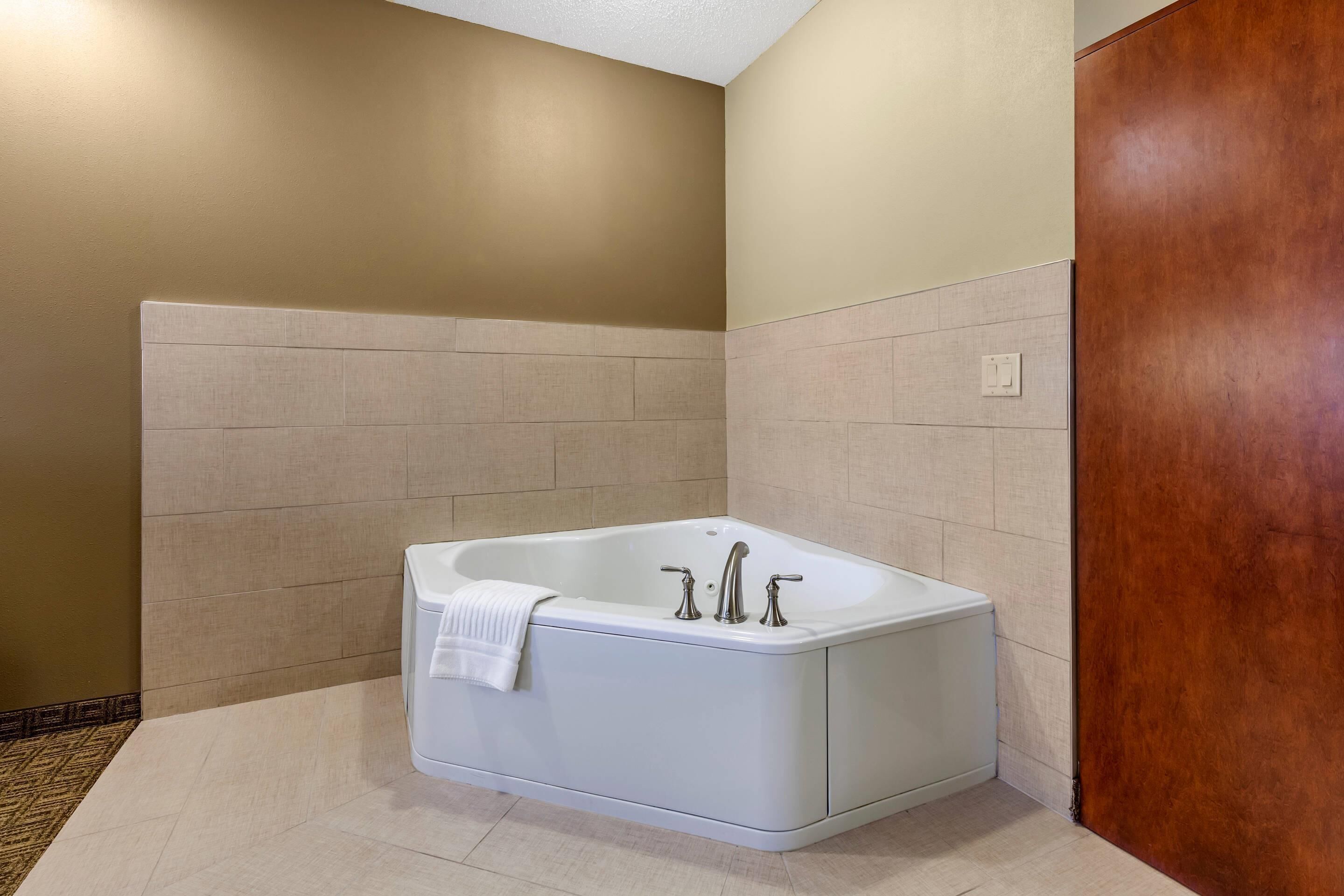 Un baño moderno con una bañera independiente, paredes color crema y una puerta de madera.