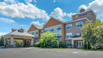 Ein Comfort Suites Hotel mit überdachter Zufahrt, mehreren Fenstern und einem Parkplatz.