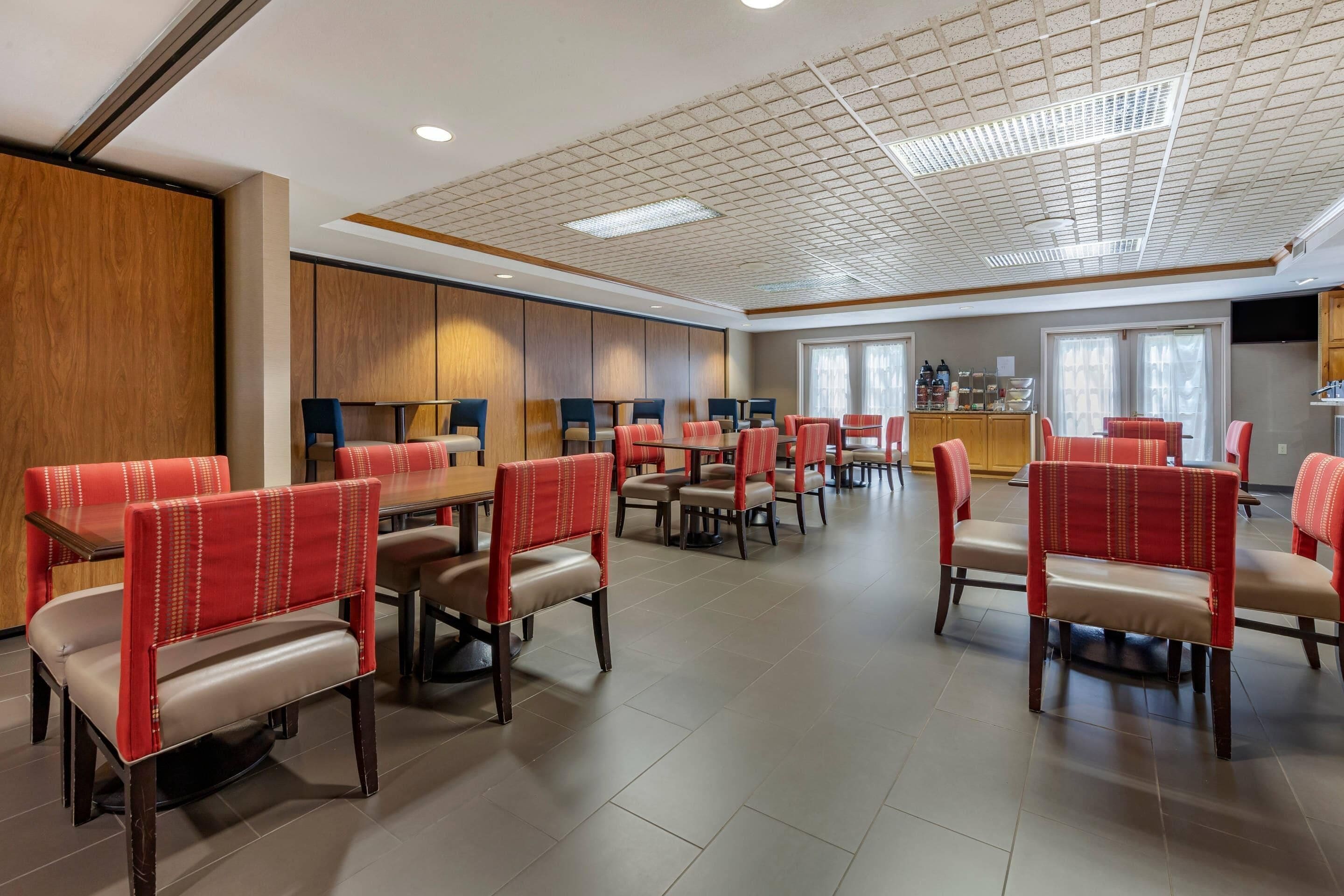 A spacious dining area with multiple tables and chairs, wooden paneling on the walls, and a ceiling with recessed lighting.