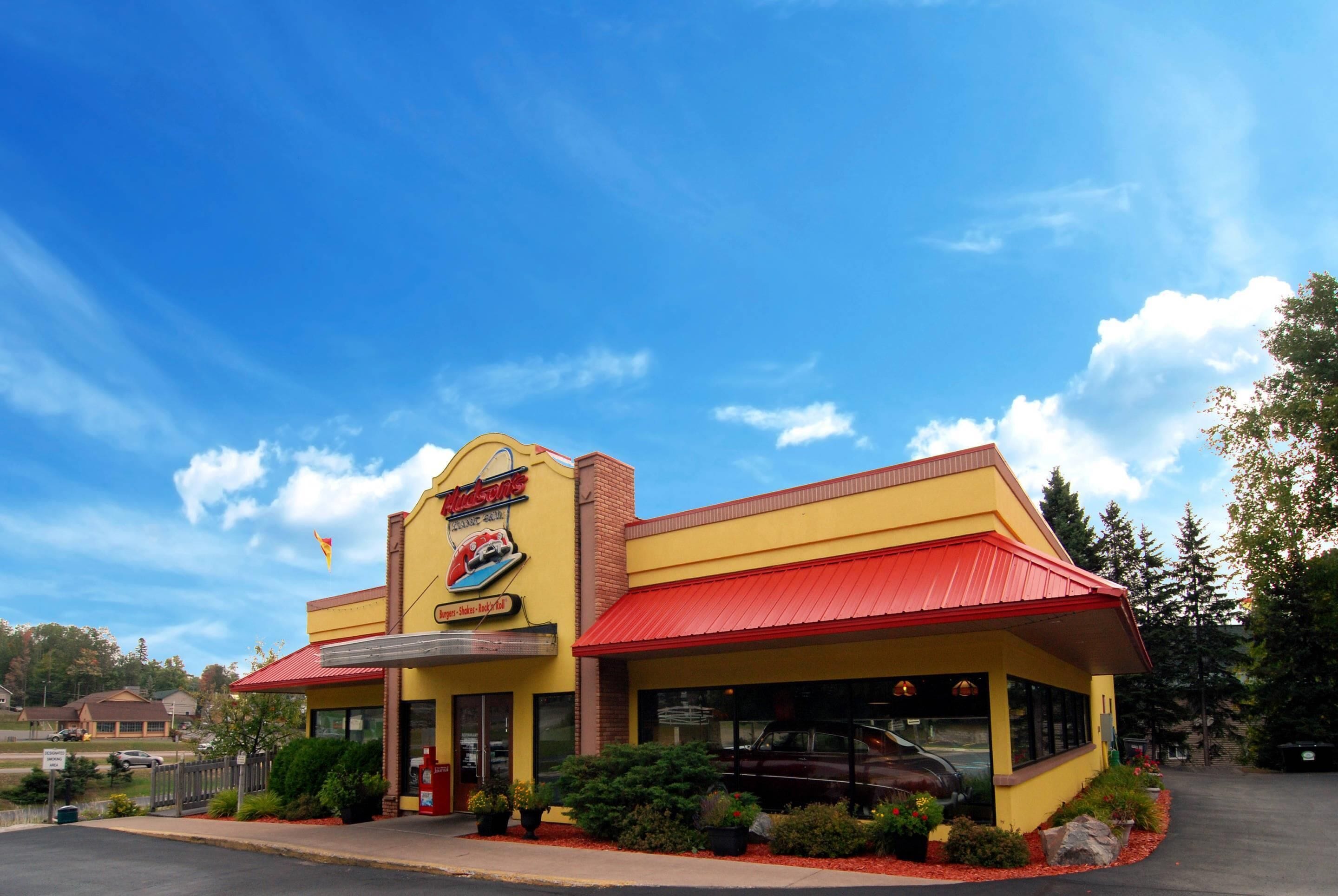 A yellow building with a red roof, a sign reading "Krispy Kreme," and a parking lot in front.