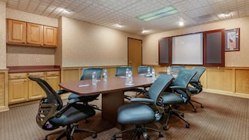 Una sala de conferencias con una mesa larga, seis sillas y una pantalla de proyector.