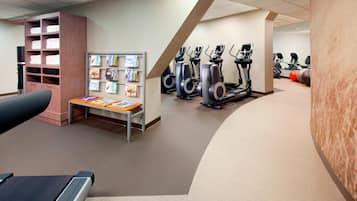 Een sportschool met fitnessapparatuur, een handdoekhouder en een prikbord met folders.