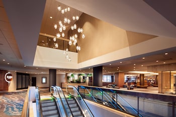 A spacious hotel room with a large window offering a city view, a comfortable sofa, a dining area, and a modern lamp. at The Westin Seattle