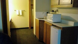 A compact kitchen with a microwave, sink, and a refrigerator. - Will Rogers Inn (Claremore)
