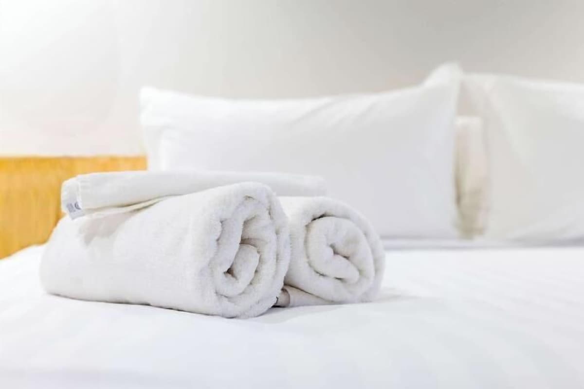 Una cama bien tendida con sábanas y almohadas blancas.