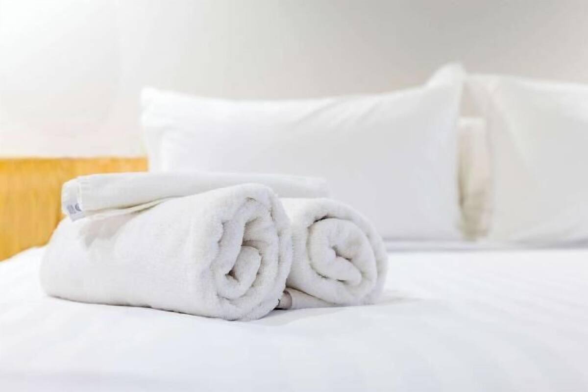 A neatly made bed with white linens and pillows.