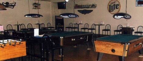 Une salle de billard équipée de plusieurs tables, de chaises et de ventilateurs de plafond.