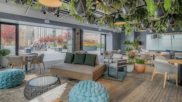 A modern lounge area with seating, a sofa, and hanging plants.