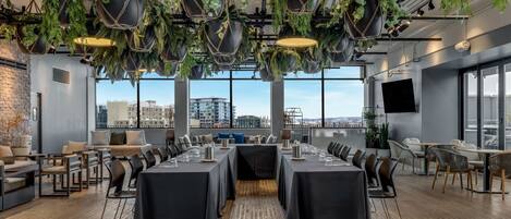 A modern conference room with black tables, chairs, and hanging plants.