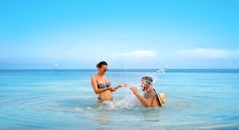 A jet ski trail in turquoise water with a beach and trees in the background. at Ocean Key Resort - A Noble House Resort