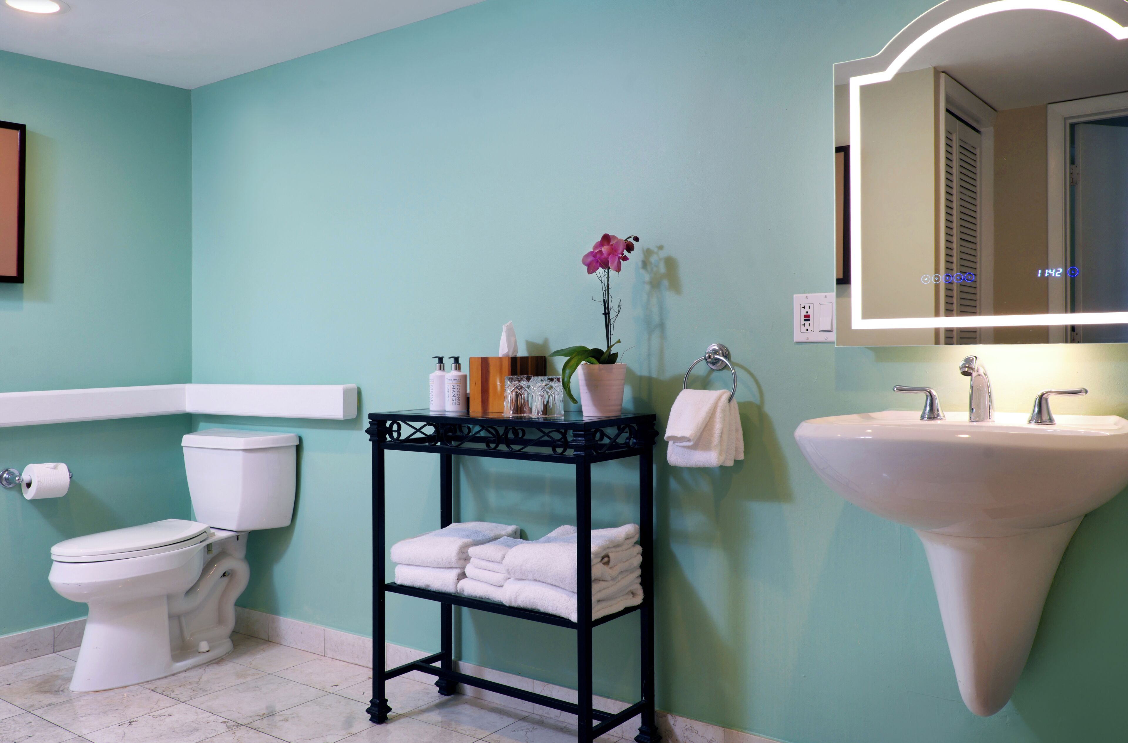 A bathroom with a toilet, sink, and a vanity table with towels and toiletries.