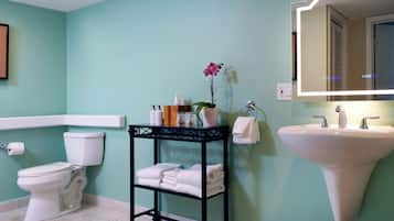 A bathroom with a toilet, sink, and a vanity table with towels and toiletries.