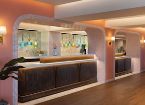 A reception area with a wooden reception desk, a tiled wall, and a hanging light fixture. - Ocean Key Resort - A Noble House Resort (Key West)