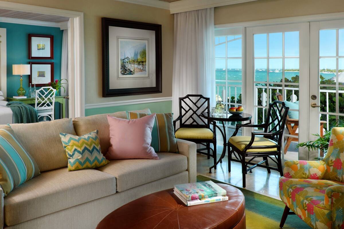 A cozy living room with a beige sofa, a coffee table, and a view of the ocean through large windows.