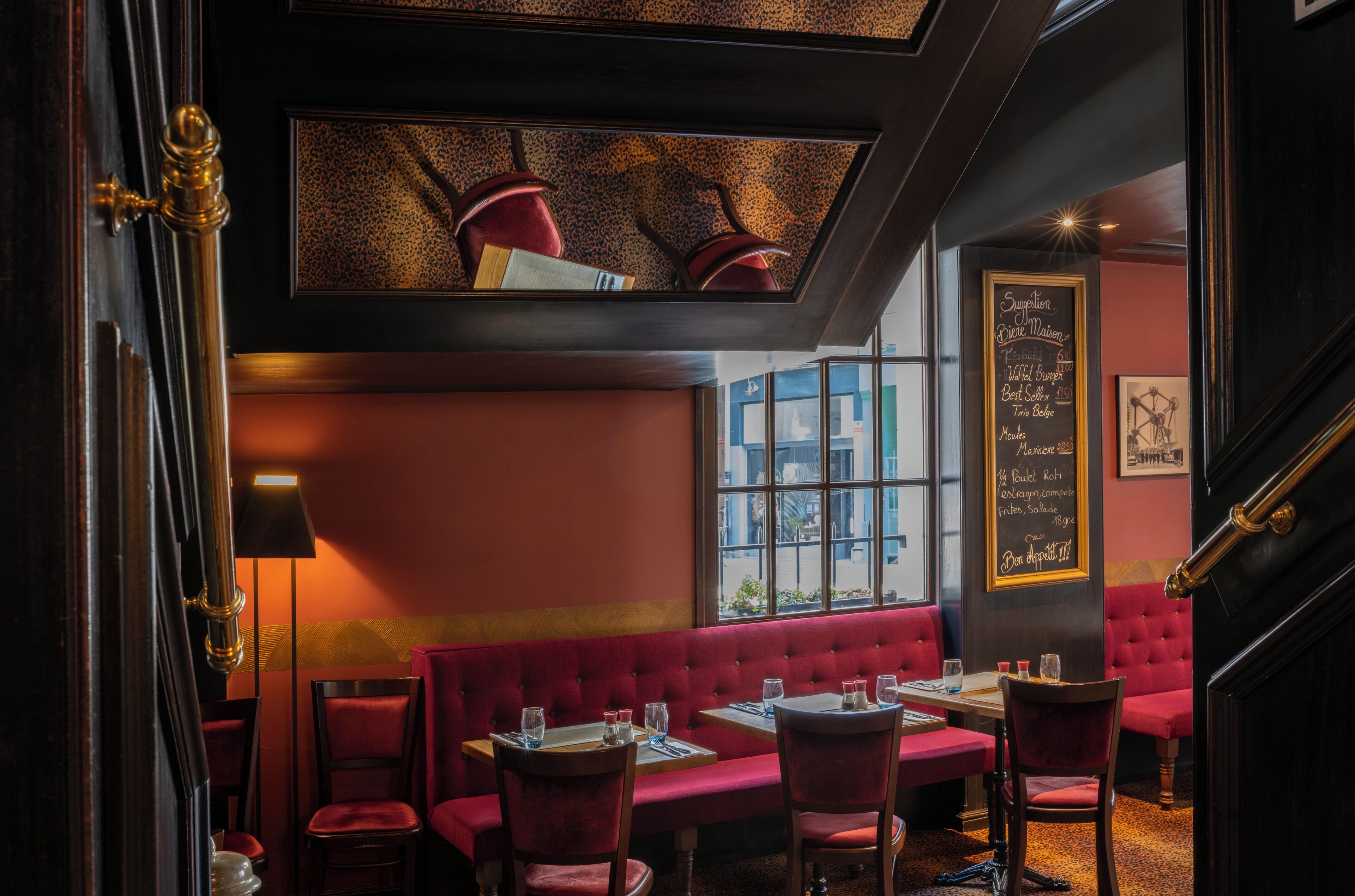 A restaurant interior with red upholstered booths, a black ceiling, and a chalkboard menu.