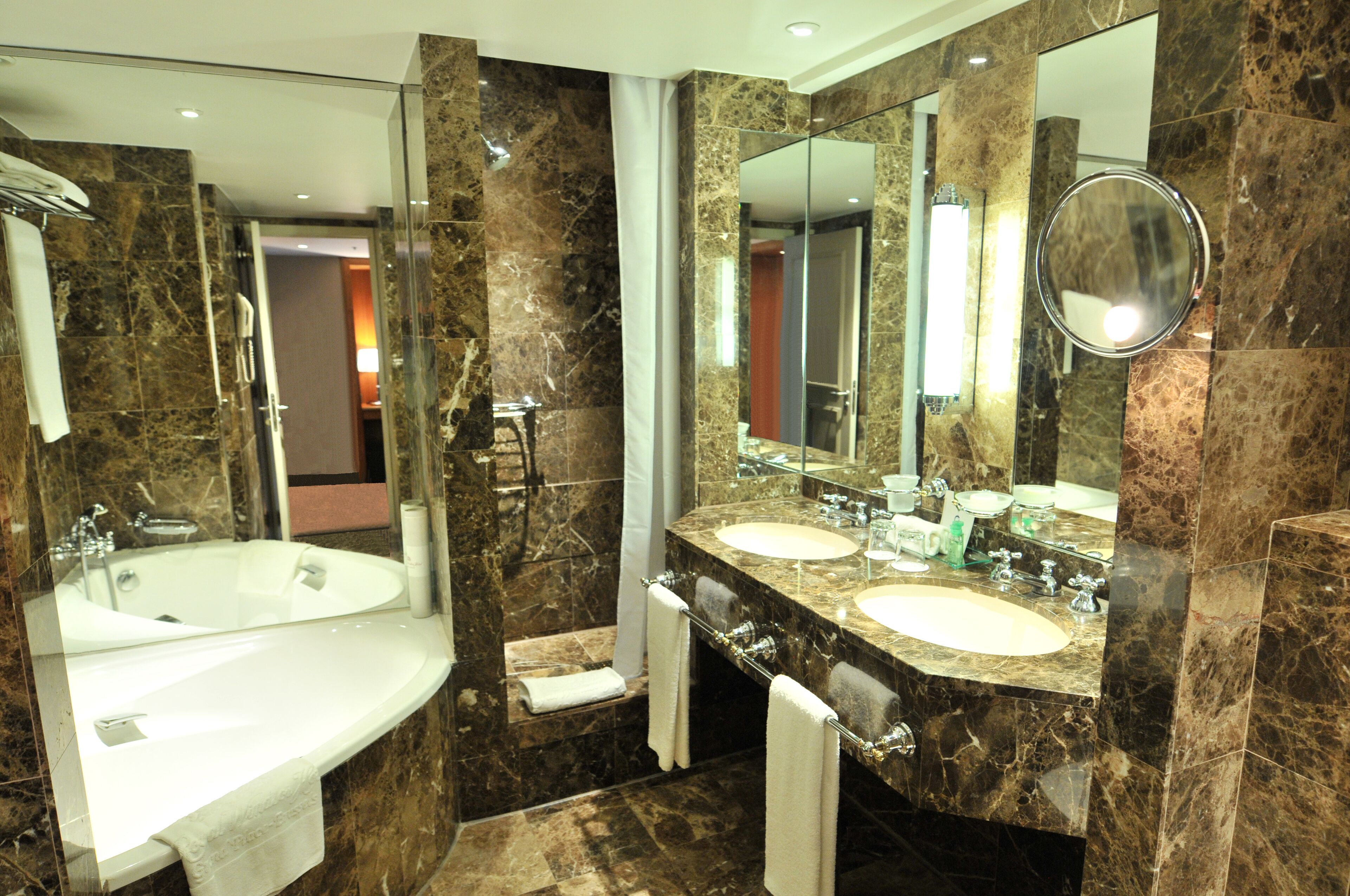 A modern bathroom with two sinks, a large mirror, and a bathtub.
