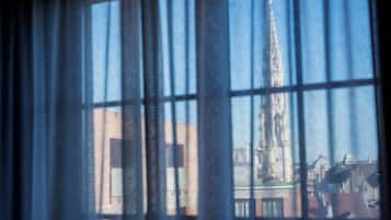 Una ventana con barrotes a través de los cuales se ve un edificio con una aguja alta.