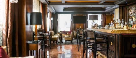 A bar area with a polished wooden floor, leather seating, and a bar counter with various bottles.