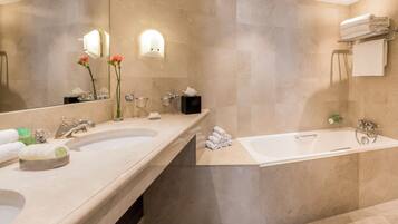 A modern bathroom with two sinks, a bathtub, and a large mirror.