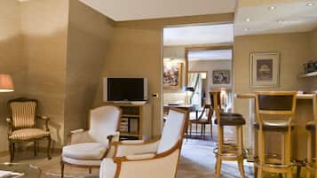 A spacious living room with a flat-screen TV, a dining area with a table and chairs, and a bar area with stools.