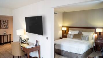 Une chambre d’hôtel équipée d’un bureau, d’une chaise, d’un téléviseur à écran plat, d’un lit avec des oreillers, de lampes de chevet et d’une tête de lit.