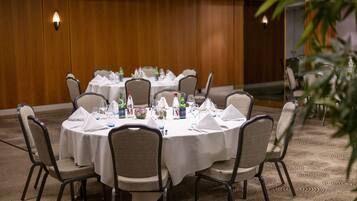 A conference room with round tables, chairs, and a wooden wall.