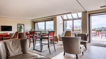Ein modernes Hotelzimmer mit Essbereich, großen Fenstern und Blick auf die Stadt.