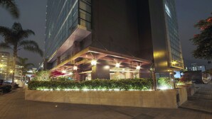 Un edificio moderno con fachada de vidrio y un área de entrada bien iluminada con asientos al aire libre.