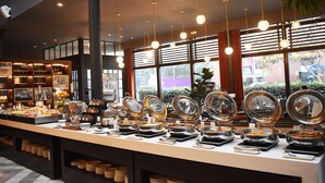 A buffet setup with various food stations and a large window view. - El Pardo Lima - A DoubleTree by Hilton Hotel (Lima)