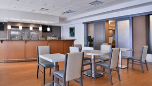 A modern dining area with a bar, wooden flooring, and contemporary furniture. - Holiday Inn Hotel & Suites Rochester - Marketplace by IHG (Rochester)