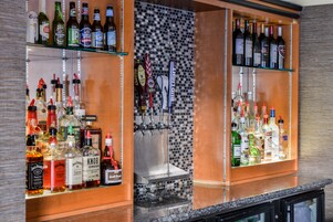 Uma área de bar com prateleiras cheias de garrafas de bebidas e um sistema de torneiras.